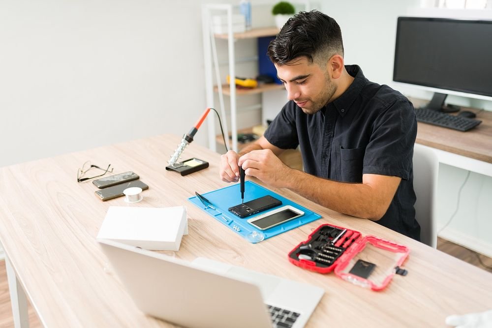 Gadget Care technician repairing a smartphone at a workbench in Island Bay